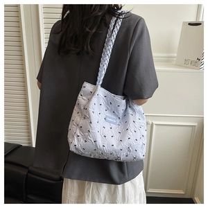 Close-up of quilted bubble fabric tote bag featuring black bow patterns and woven strap