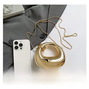 Close-up of a gold crescent acrylic handbag with mirror finish and slim metal chain strap