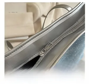 Close-up of smooth silver metal zipper on metallic silver synthetic leather tote bag