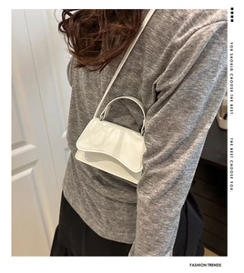 Chic white mini crossbody bag shown worn on shoulder in a casual lifestyle setting