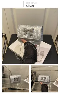 Detail of silver snake-embossed mini bag with metallic bow and fine chain strap