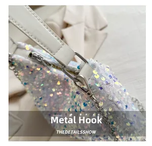 Close-up of polished silver metal hooks and iridescent sequins on a white square handbag