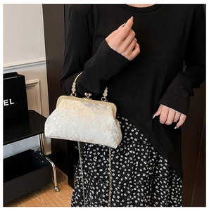 Détail d'une pochette jacquard à fleurs avec fermoir vintage et bandoulière chaîne