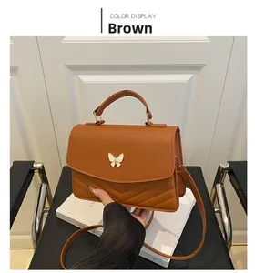 Brown handbag with V-quilted texture and white bow metal clasp on white books
