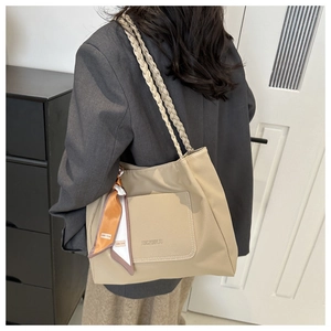 Detail of beige tote bag showing lychee grain leather texture and woven shoulder strap