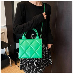 Sac fourre-tout matelassé vert vif porté par un mannequin avec bandoulière et poignée