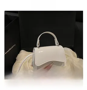 Detail of white patent leather handbag with wavy flap edge in a black gift box