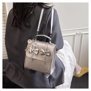 Detail of silver metallic mini backpack with 3D bows and elegant pearl pendant accessory