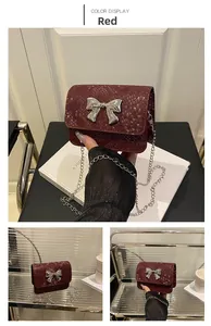 Detail view of mini red crossbody bag with snake pattern texture and silver bow buckle