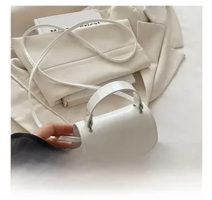 Detail of white patent leather mini square bag with glossy finish and refined metal hardware