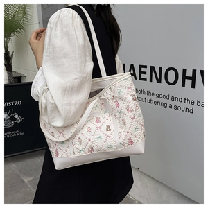 Detail of printed tote bag with cartoon bear and floral patterns on textured fabric