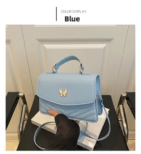 Detail of light blue crossbody bag with gold butterfly clasp and V-shaped stitching