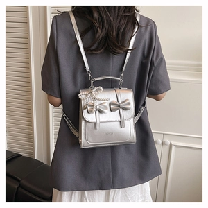 Close-up of silver backpack detail with metallic bows and pearl pendant decoration