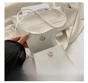 Close-up of white patent leather shoulder bag with a premium silver magnetic buckle detail