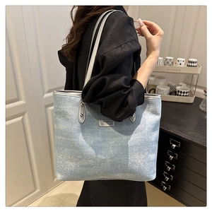 Detail of light blue glitter tote bag showing metallic shoulder straps and silver brand plate