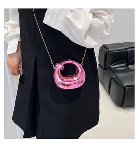 Macro detail of a bright pink metallic mini chain bag worn as a stylish waist accessory