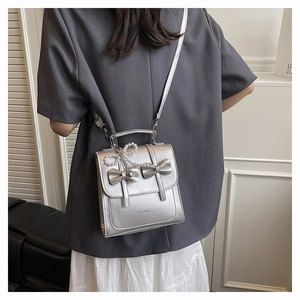 Detail of silver bow shoulder bag with pearl charm and fashion branding in casual style