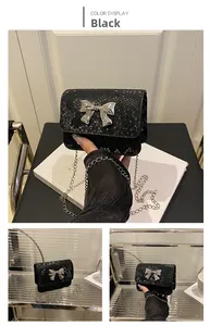 Detail view of black snakeskin texture mini chain bag with silver metal bow buckle