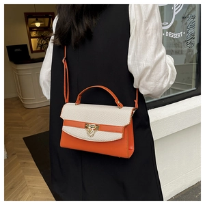 Dettaglio della borsa in pelle arancione e trama intrecciata con chiusura dorata