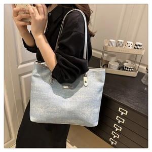 Détail du sac cabas en denim pailleté bleu clair avec plaque logo en métal argenté