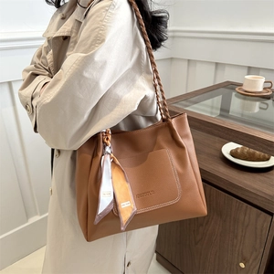 Brown leather tote bag with braided handles and decorative silk scarf for women