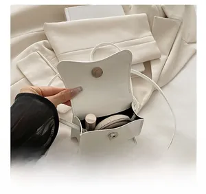 Internal capacity of white patent leather crossbody bag showing lipstick and foundation