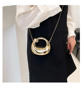Close-up of golden hollow ring evening bag with chain strap on a stylish model