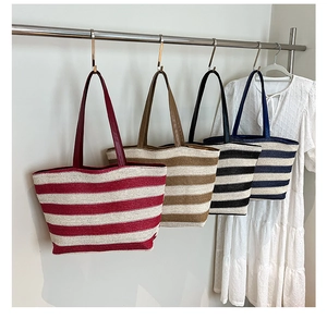 Dettaglio di quattro borse tote a righe intrecciate appese con un abito bianco estivo