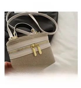 Detail of canvas and white leather box bag with golden metal zipper and top handle
