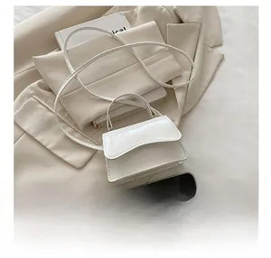 Mini white patent leather bag with handle next to a smartphone showing compact size