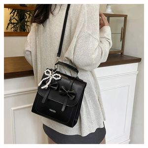 Detail of black bow shoulder bag featuring a pearl pendant and fashion embossing