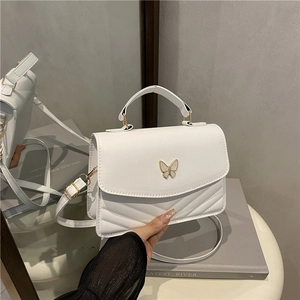 Quilted white crossbody bag with butterfly buckle shown from front and side view