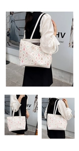 Close-up detail of white tote bag featuring pink bear prints and long shoulder straps