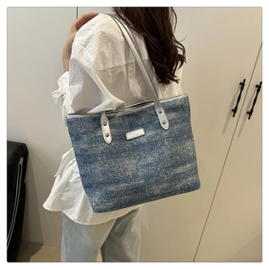 Detail of glittery denim tote bag with silver leather handles and metallic brand plate