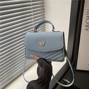 Minimalist light blue crossbody bag with golden butterfly clasp and chevron stitching