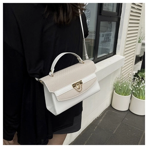 Dettaglio borsa bianca con texture, chiusura dorata e catena su sfondo minimalista