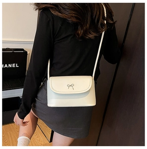 Detailed back view of a cream mini crossbody bag with a chic bow metal clasp on model