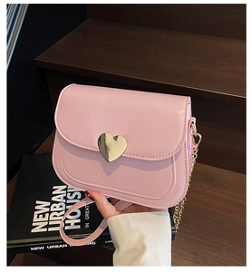 Detail of pink PU leather handbag featuring a polished gold heart-shaped metal lock