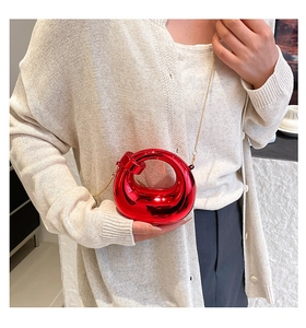 Macro detail of red mirror acrylic mini bag with twisted handle and metal chain strap