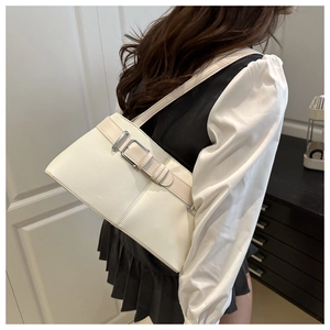 Detail view of cream white shoulder bag featuring a wide strap with silver metal buckle