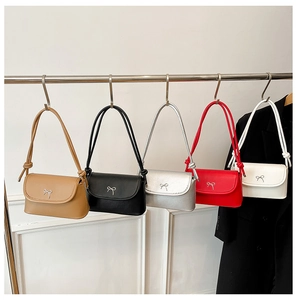 Five colored PU leather shoulder bags with bow metal buckles hanging on hooks