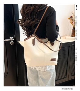Detail of a large cream-colored tote bag with contrast brown trim and shoulder straps