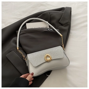 Detail of silver sequin shoulder bag with golden horseshoe buckle on grey blazer