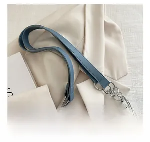 Close-up of denim tote bag featuring frayed edges and silver chain leather strap