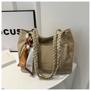 Dettaglio della borsa tote in pelle martellata con manico intrecciato e foulard di seta