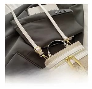 Detail of adjustable buckle and texture on beige canvas and white leather crossbody bag