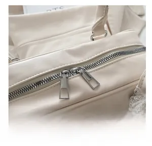 Detailed close-up of the smooth silver metal zipper on a cream-colored leather handbag