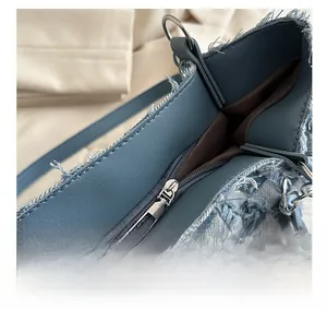 Detail of vintage blue denim tote with metallic zipper and frayed edges decoration