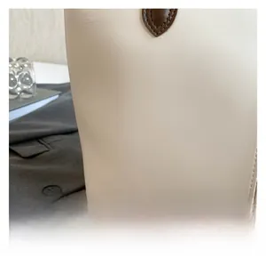 Close-up of ivory leather tote showing smooth texture and brown teardrop strap accents