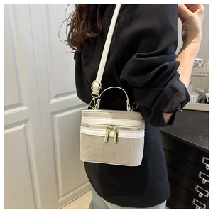 Detail of beige textured box bag with white trim and adjustable leather shoulder strap